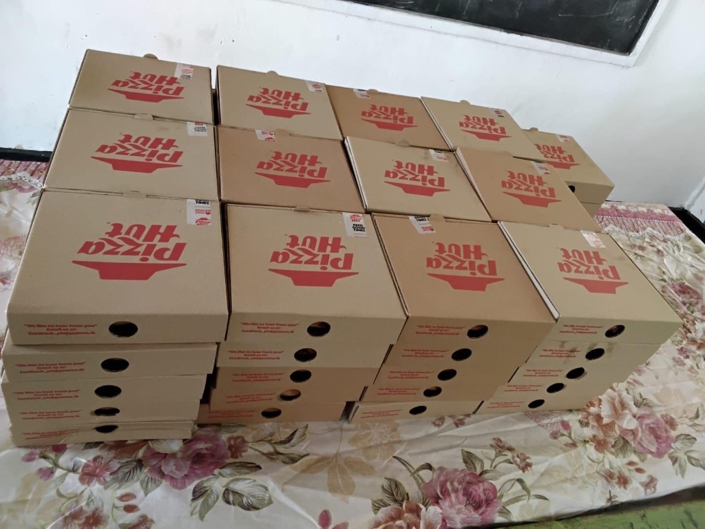 Stacks of pizza boxes ready on a table before the Children's Day celebration