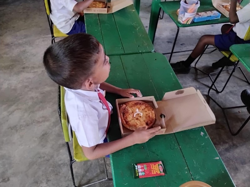 Student seated at a desk with an open pizza box in the classroom